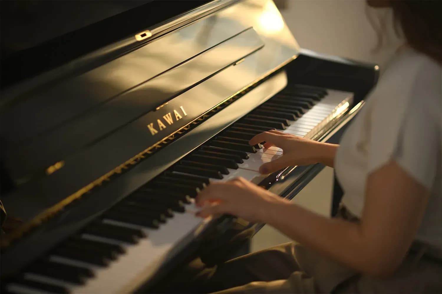 Hands on the keys of a Kawai upright piano